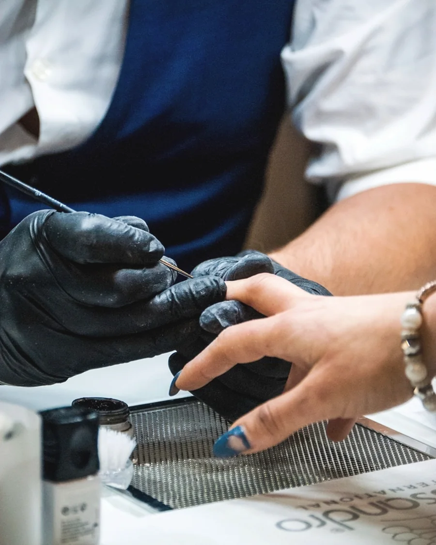 Stock photo of a nail technician filing a client's nail